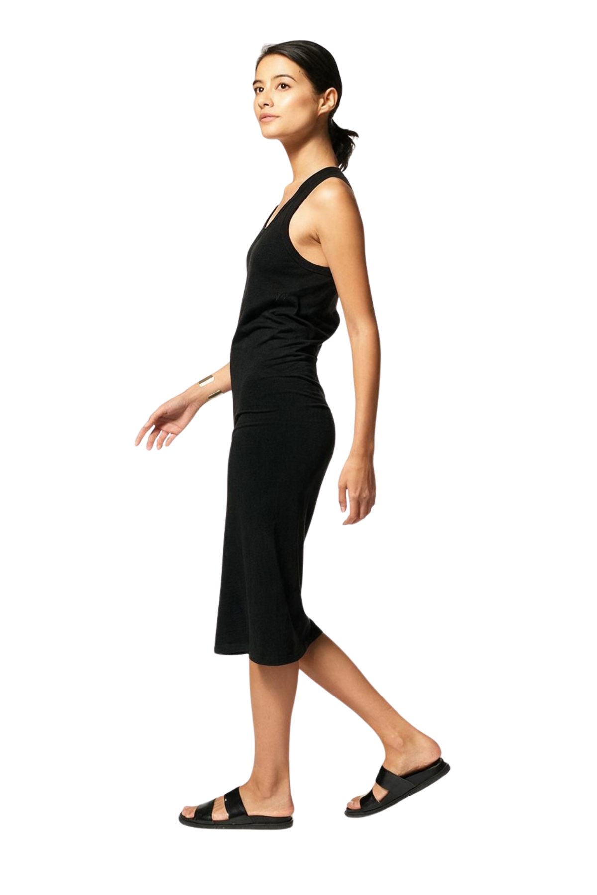 A woman modeling a black sleeveless midi dress with a fitted silhouette and side slit, paired with black slide sandals, shown against a plain white background.