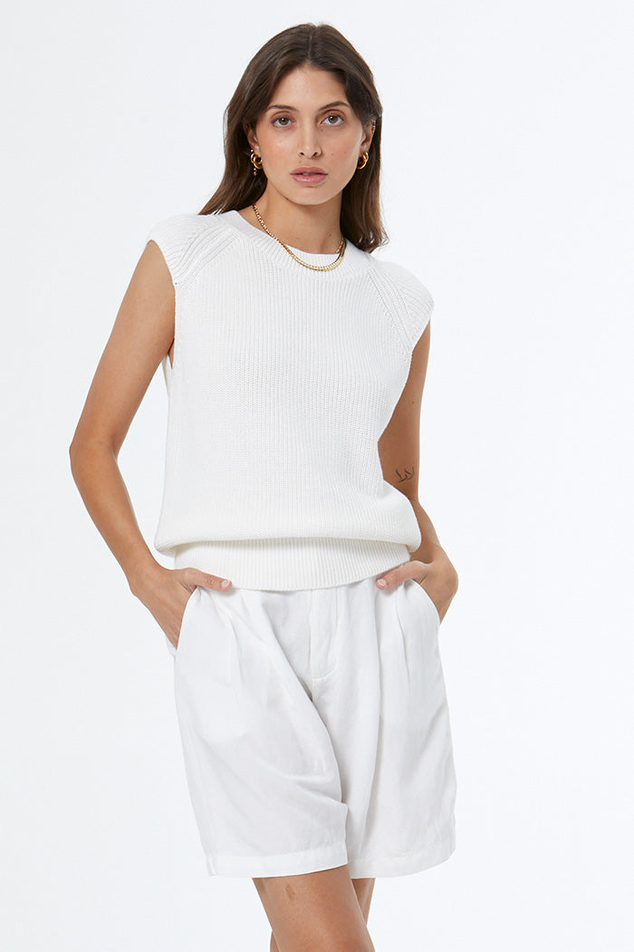 Woman wearing a white sleeveless top and white shorts on a white background