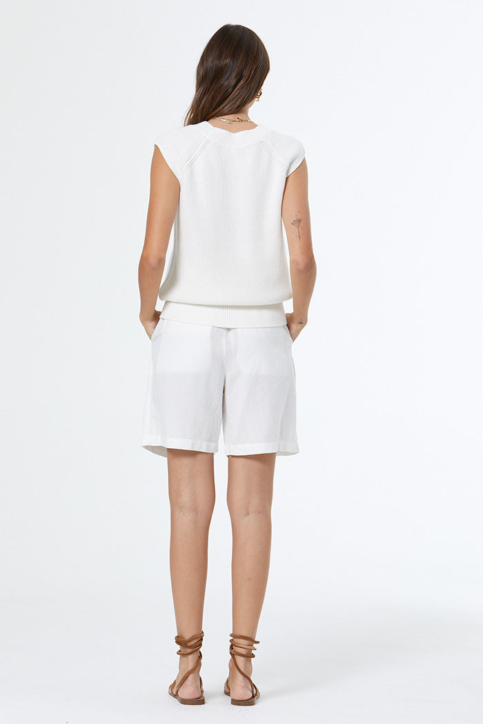 Woman wearing a white sleeveless top and shorts on a white background