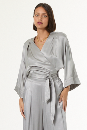 Woman wearing a silver satin blouse on a white background