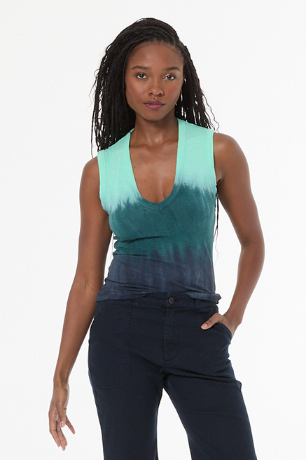 Woman wearing a green and blue tie-dye tank top and black pants on a white background