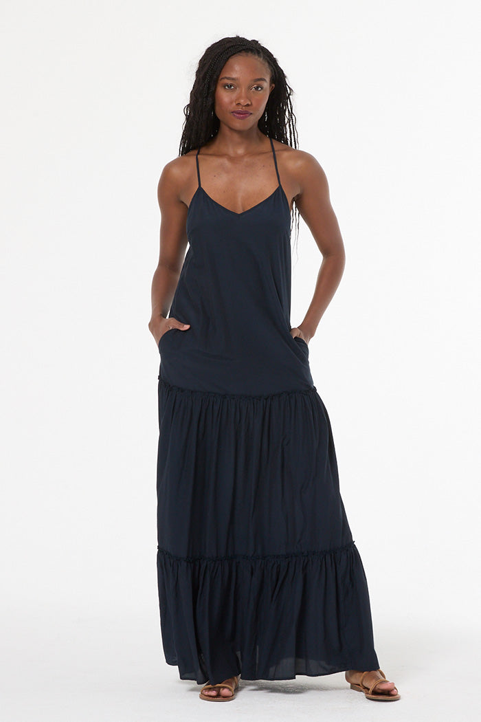 Woman wearing a navy blue dress with tiered skirt on a white background