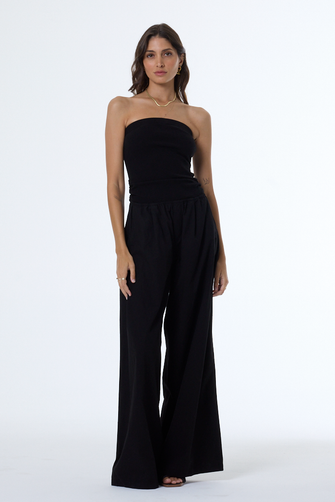 Woman wearing a black strapless jumpsuit on a white background