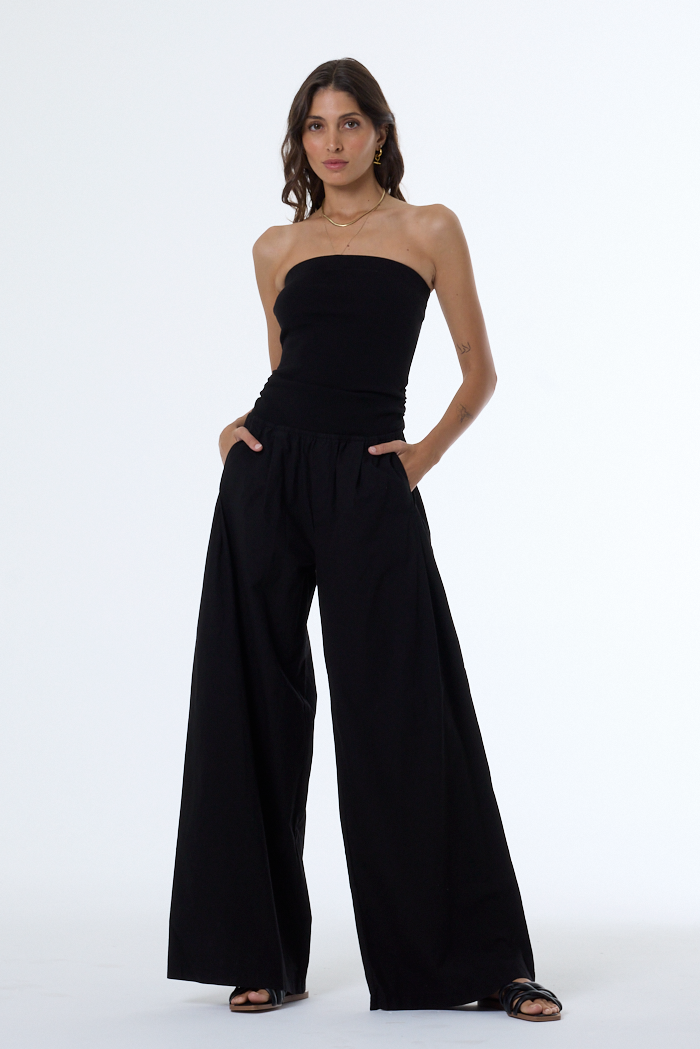 Woman wearing a black strapless jumpsuit on a white background