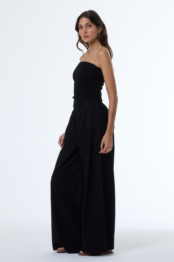 Woman wearing a black strapless jumpsuit on a white background