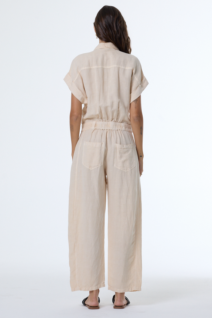 Person wearing a beige jumpsuit on a white background
