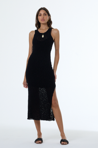 Woman wearing a black sleeveless dress with a slit on a white background