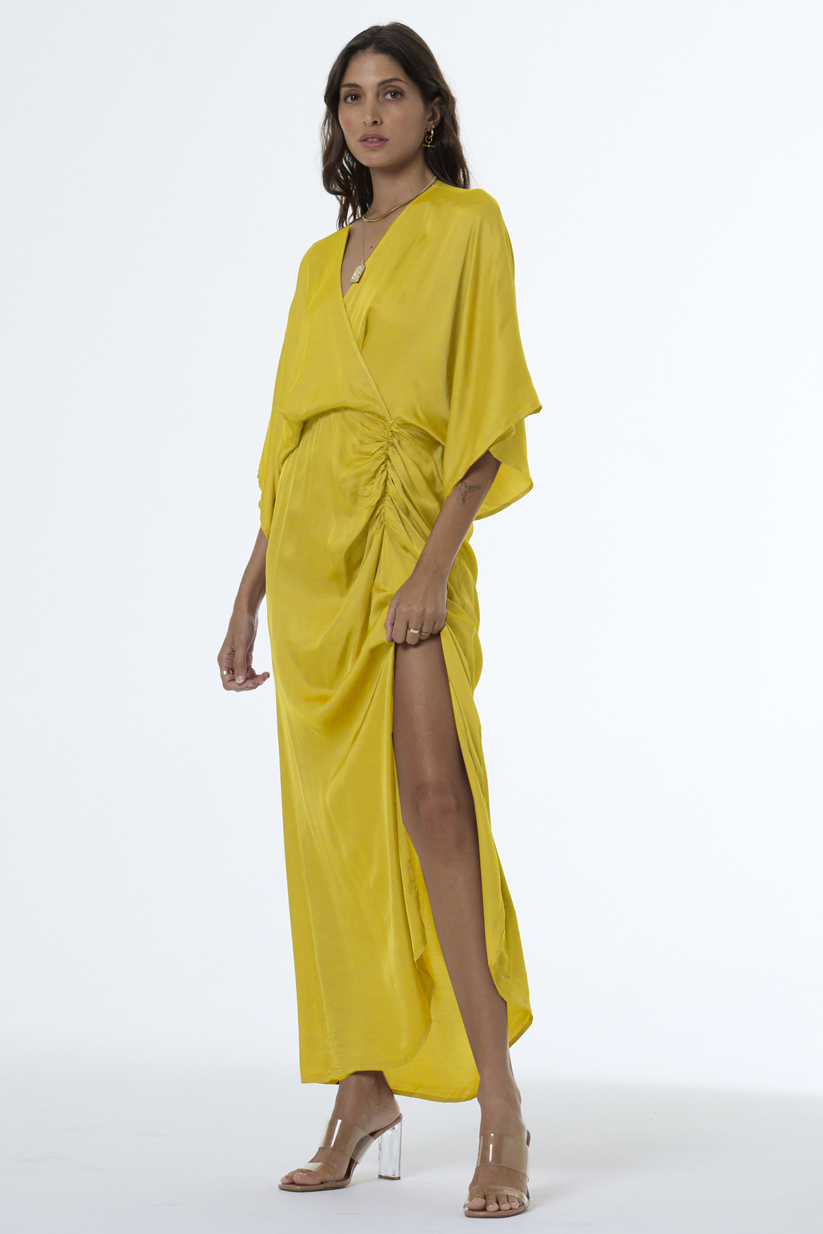 Woman wearing a yellow dress with a slit on a white background