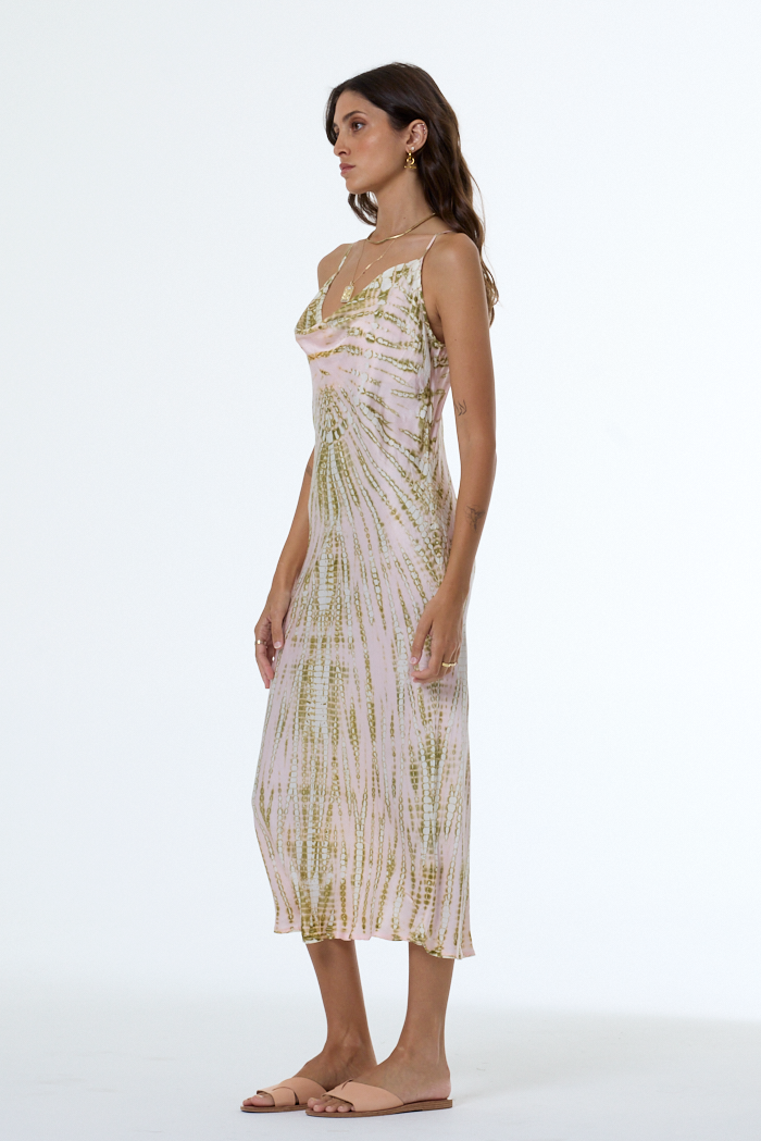 Woman wearing a light pink dress with green patterns on a white background
