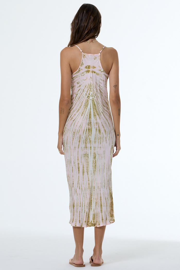Woman wearing a light pink dress with green patterns on a white background