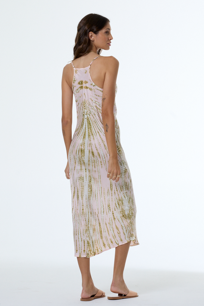 Woman wearing a light pink dress with green patterns on a white background