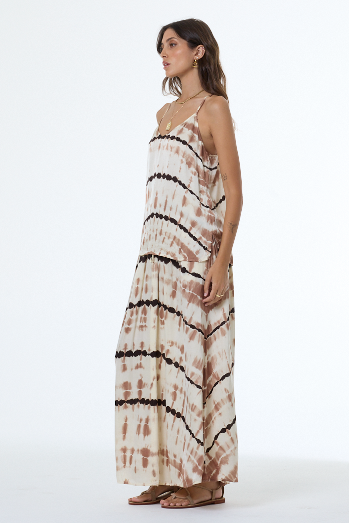 Woman wearing a tie-dye camisole and skirt with black patterns on a white background