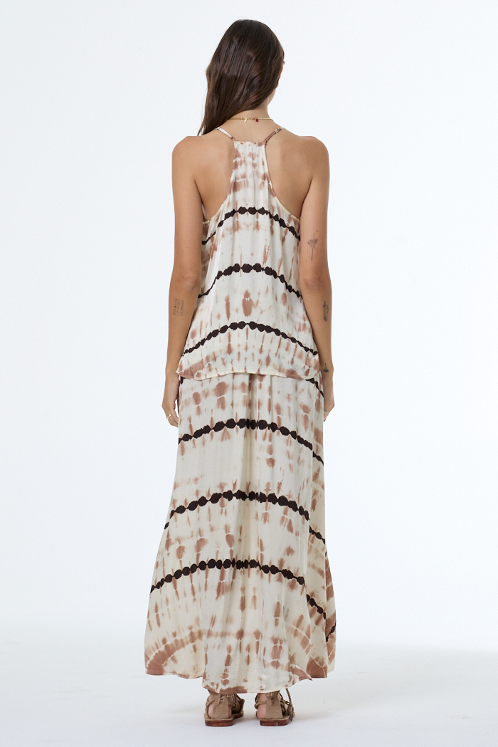 Woman wearing a tie-dye camisole and skirt with black patterns on a white background