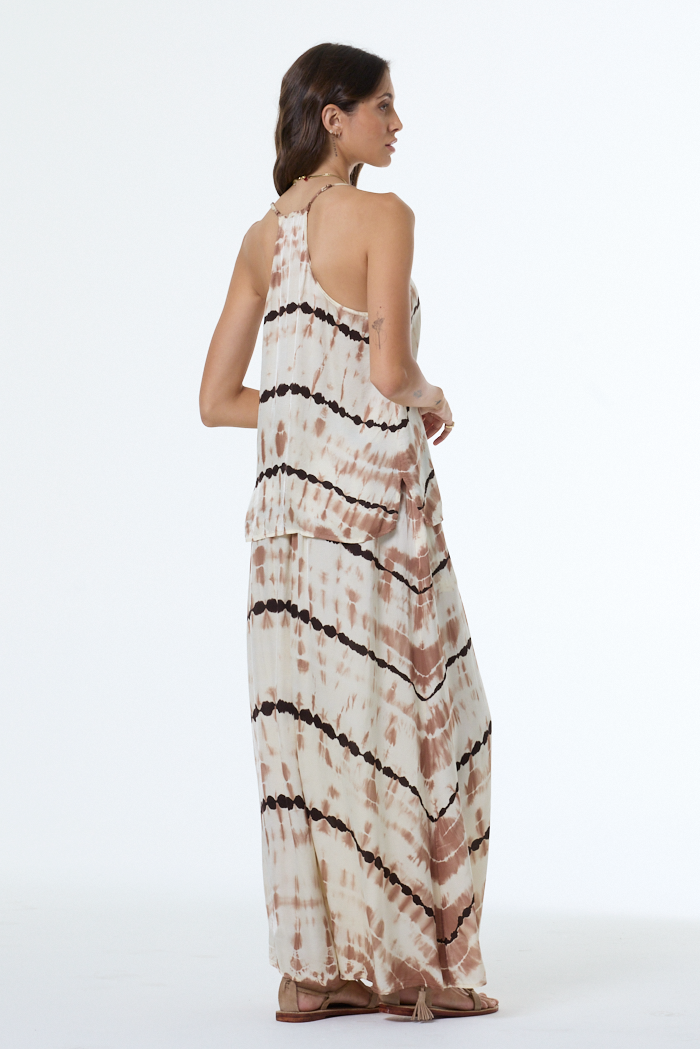 Woman wearing a tie-dye tank and skirt with black stripes on a white background