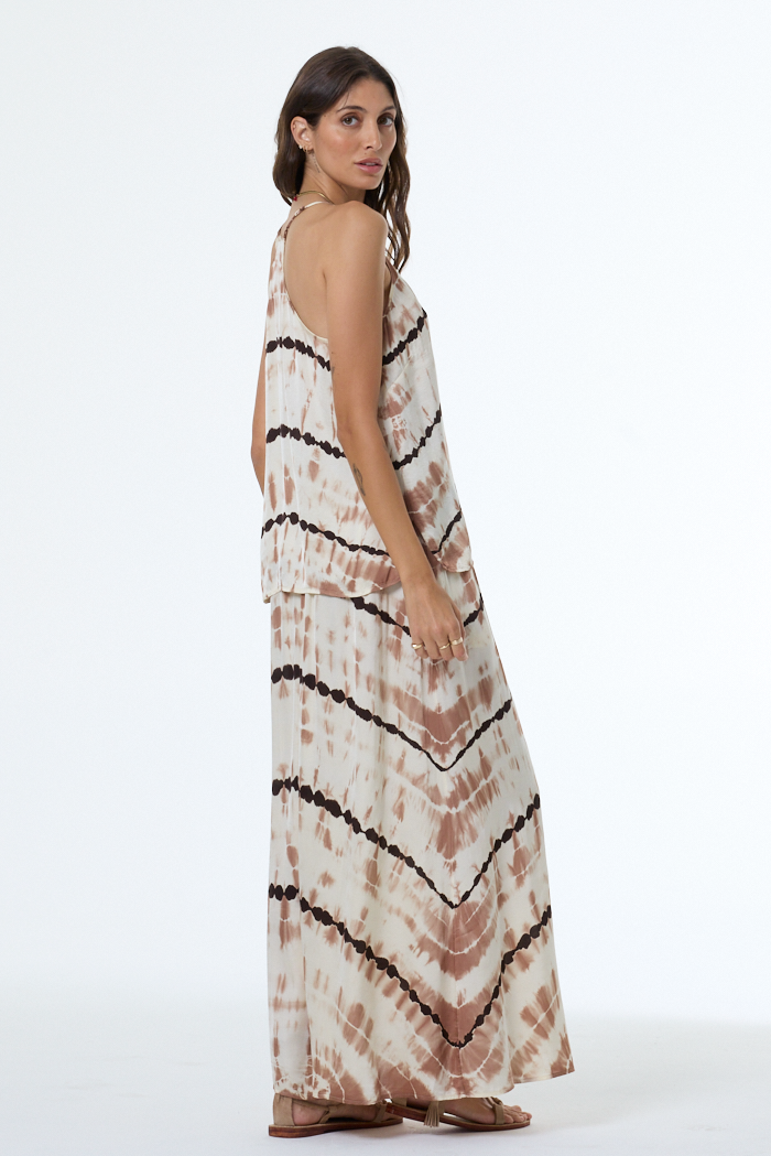 Woman wearing a tie-dye tank and skirt with black stripes on a white background