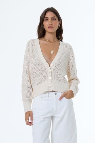 woman wearing a white boucle cardigan with white background