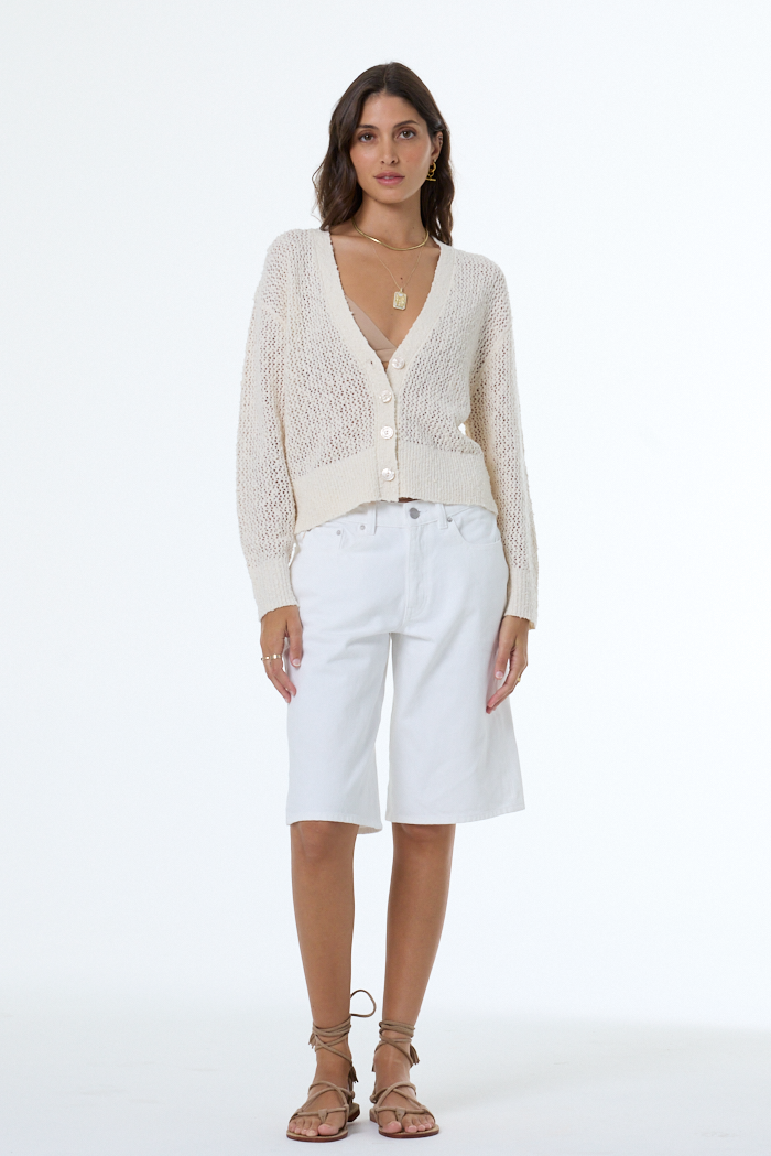 woman wearing a white boucle cardigan with white background