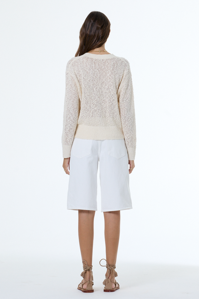 woman wearing a white boucle cardigan with white background