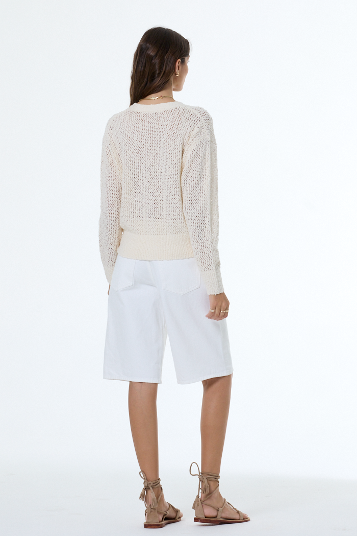 woman wearing a white boucle cardigan with white background