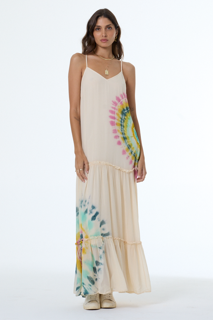 Woman wearing a long, light-colored dress with tie-dye patterns on a white background
