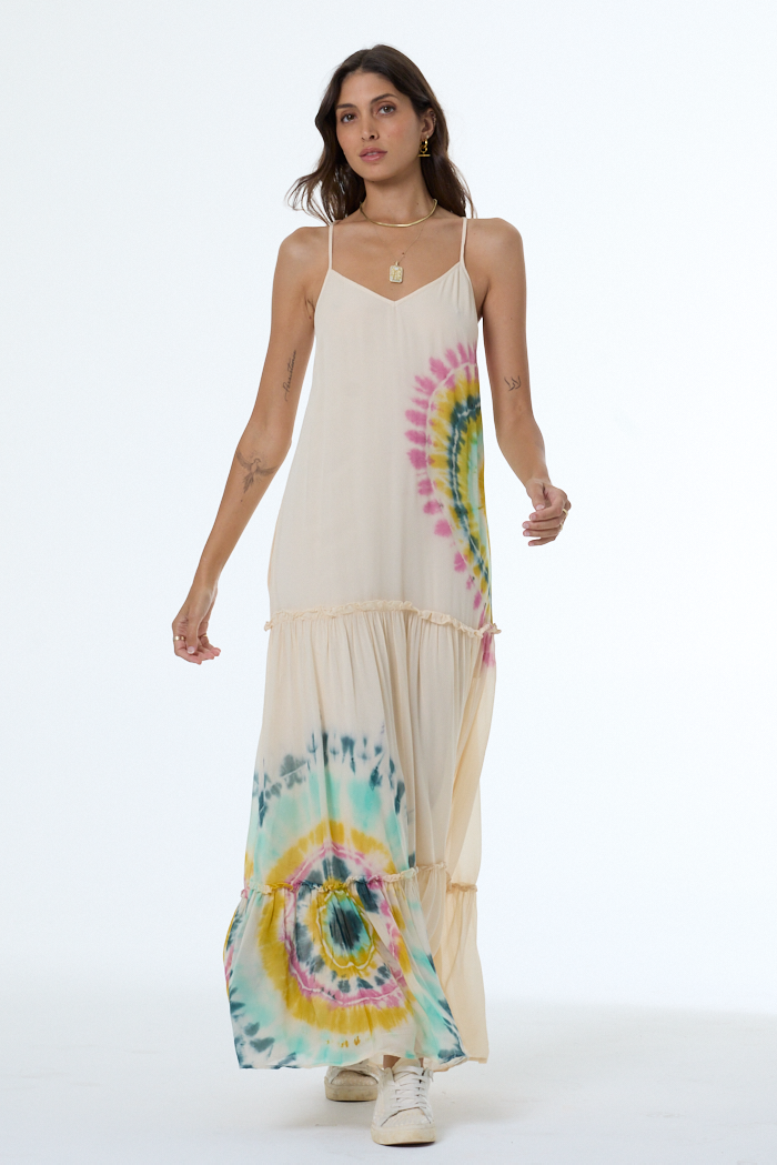 Woman wearing a long dress with tie-dye patterns on a white background