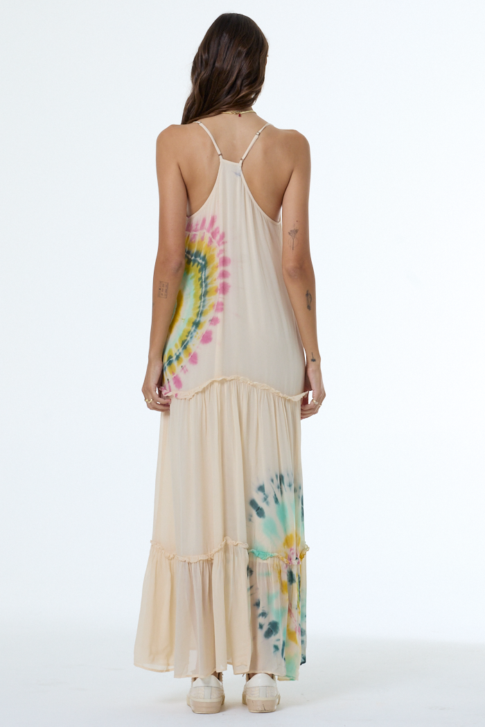 Woman wearing a long dress with tie-dye patterns on a white background