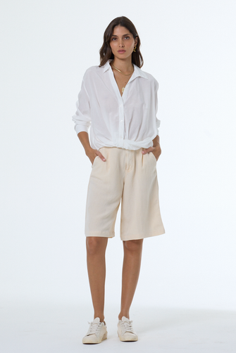 Woman wearing a white shirt and beige shorts on a white background
