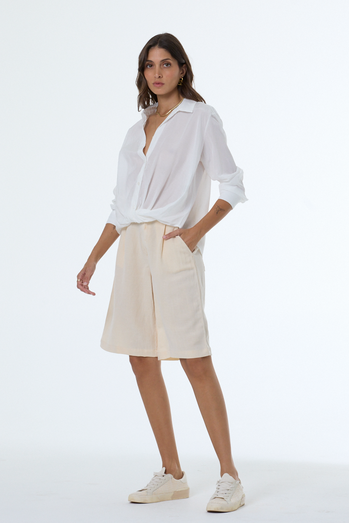 Woman wearing a white shirt and beige shorts on a white background