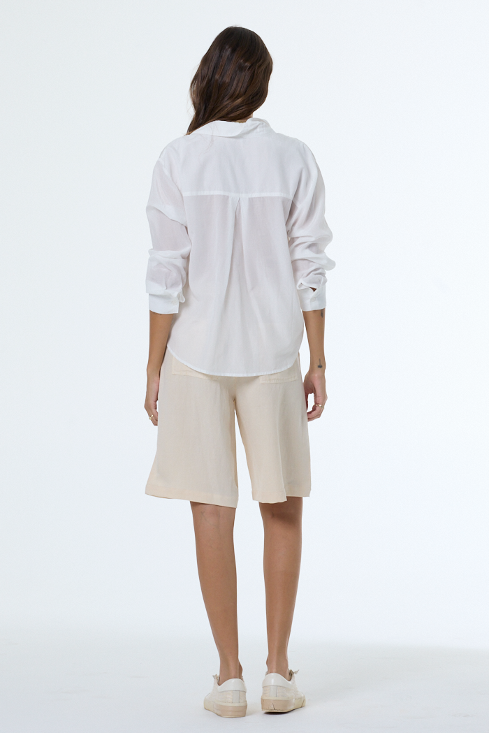 Person wearing a white shirt and beige shorts on a white background