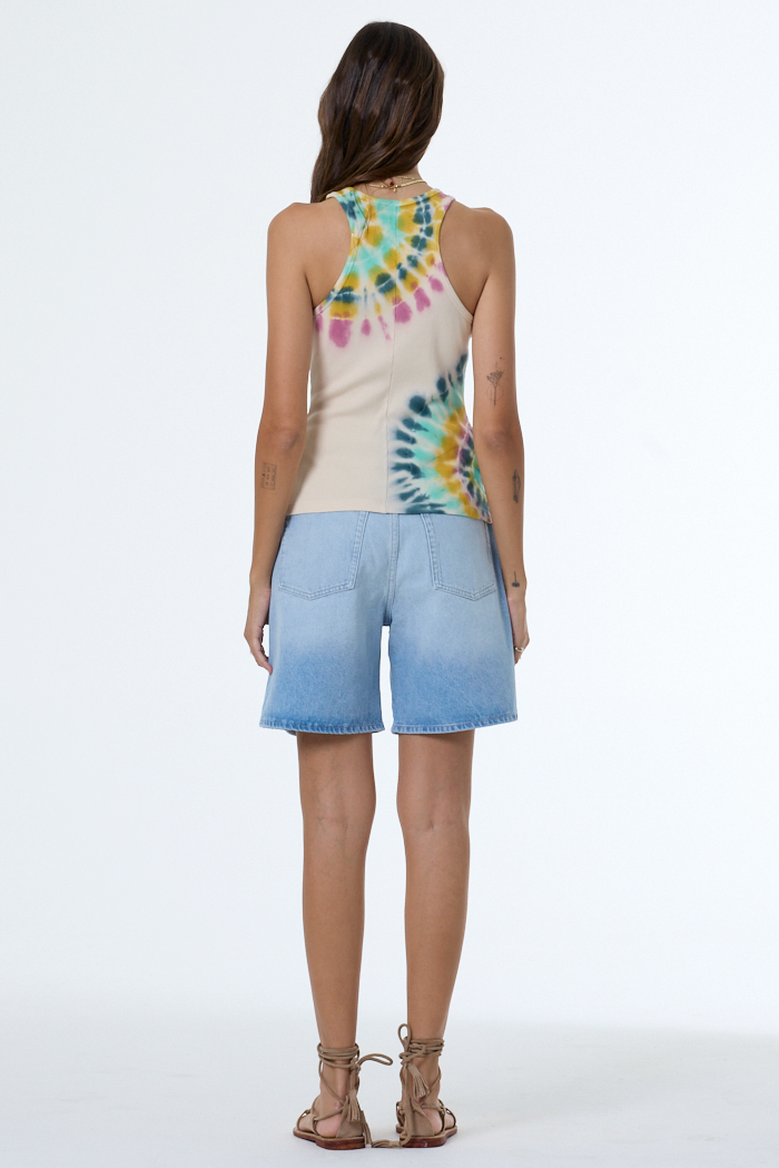 Person wearing a tie-dye sleeveless top and denim shorts on a white background