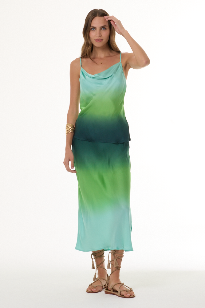 Woman wearing a green gradient tank and skirt set with a white background