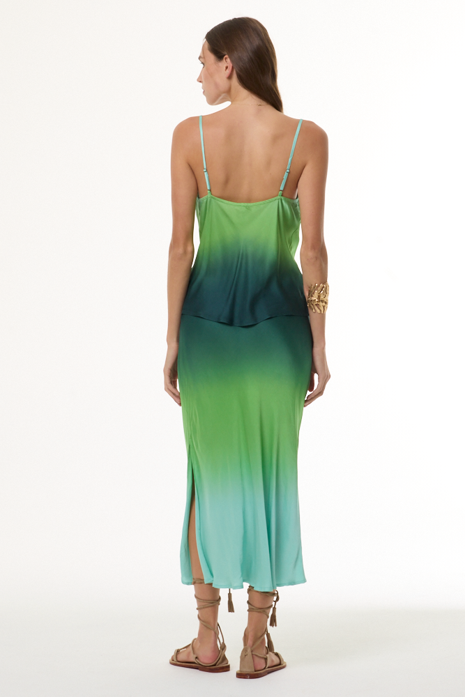 Woman wearing a green gradient tank and skirt set with a white background