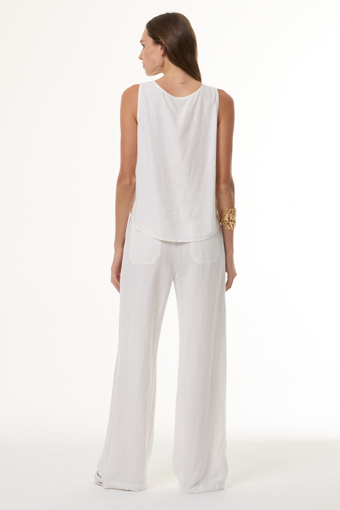 Woman wearing a white sleeveless top and pants on a white background