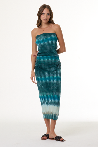 Woman wearing a turquoise strapless tie-dye dress on a white background