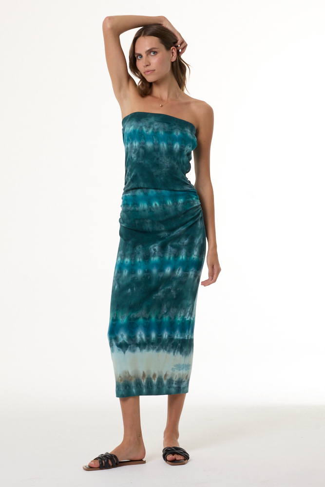 Woman wearing a turquoise strapless tie-dye dress on a white background