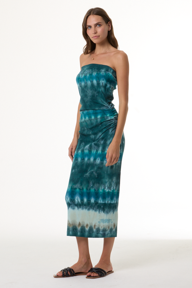 Woman wearing a turquoise strapless tie-dye dress on a white background