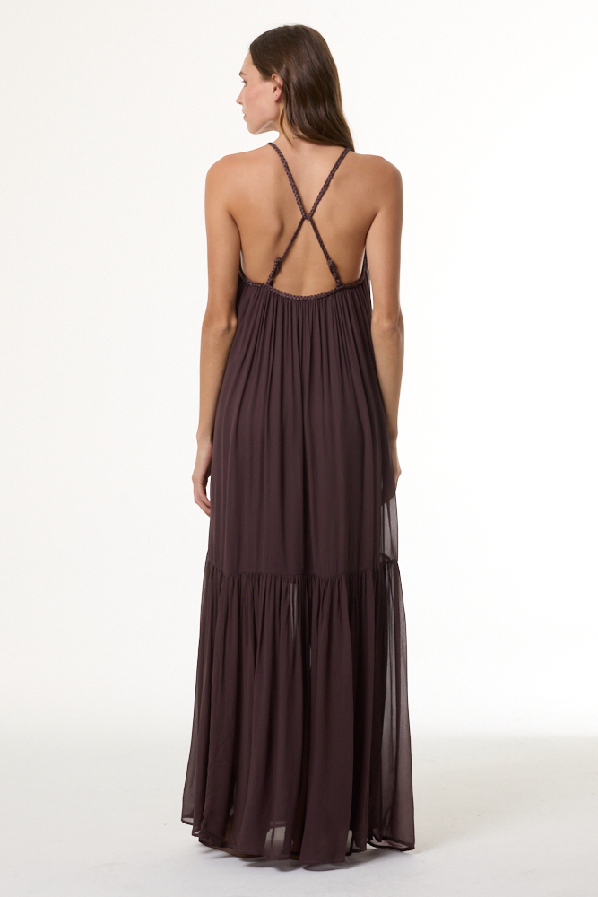 Woman wearing a long brown dress with thin straps on a white background