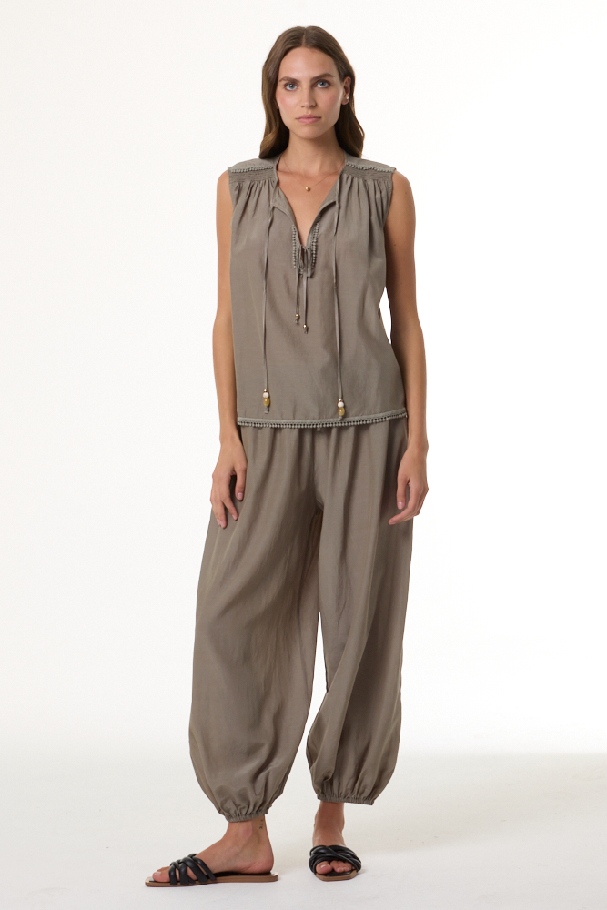 Woman wearing a beige sleeveless top and pants on a white background