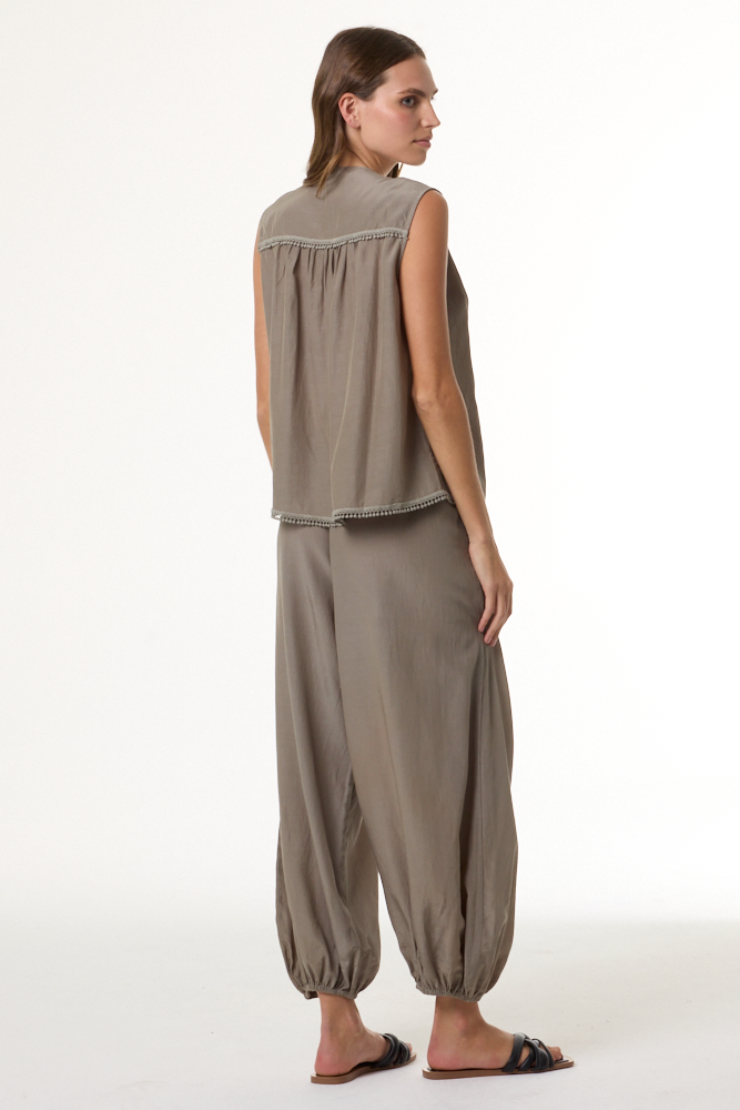 Woman wearing a sage sleeveless top and harem pants on a white background