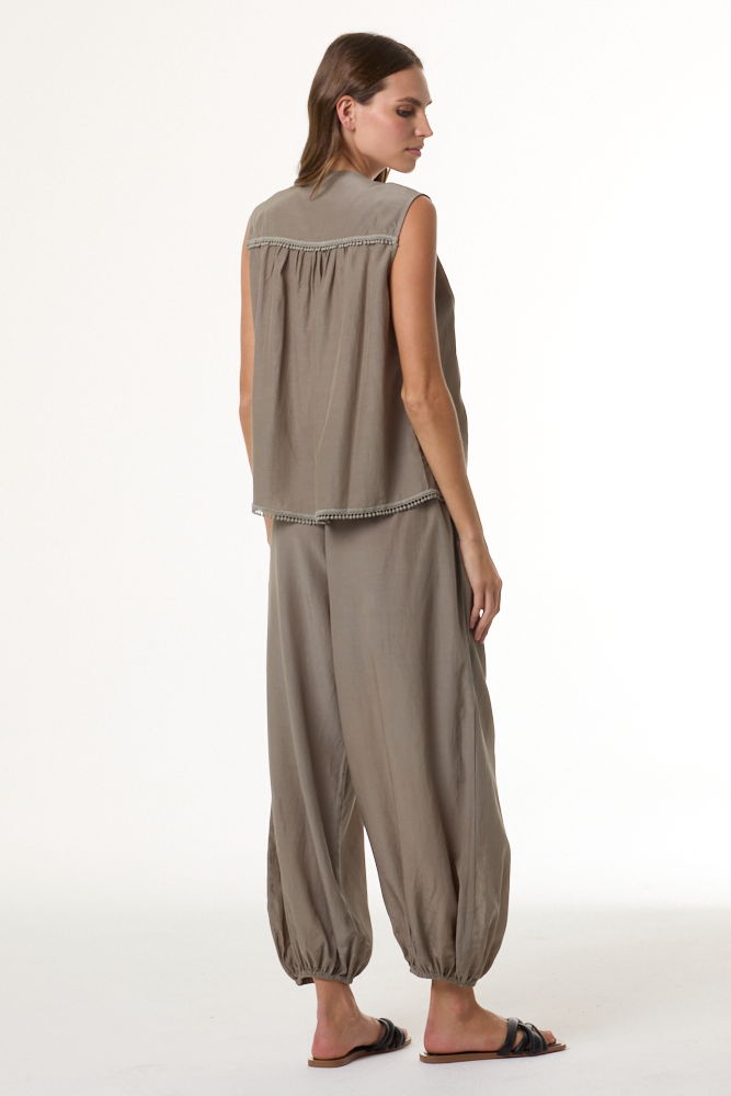 Woman wearing a beige sleeveless top and pants on a white background
