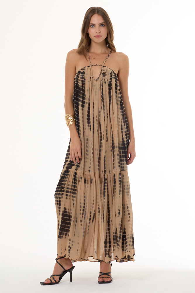 Woman wearing a tan and black tie-dye dress on a white background