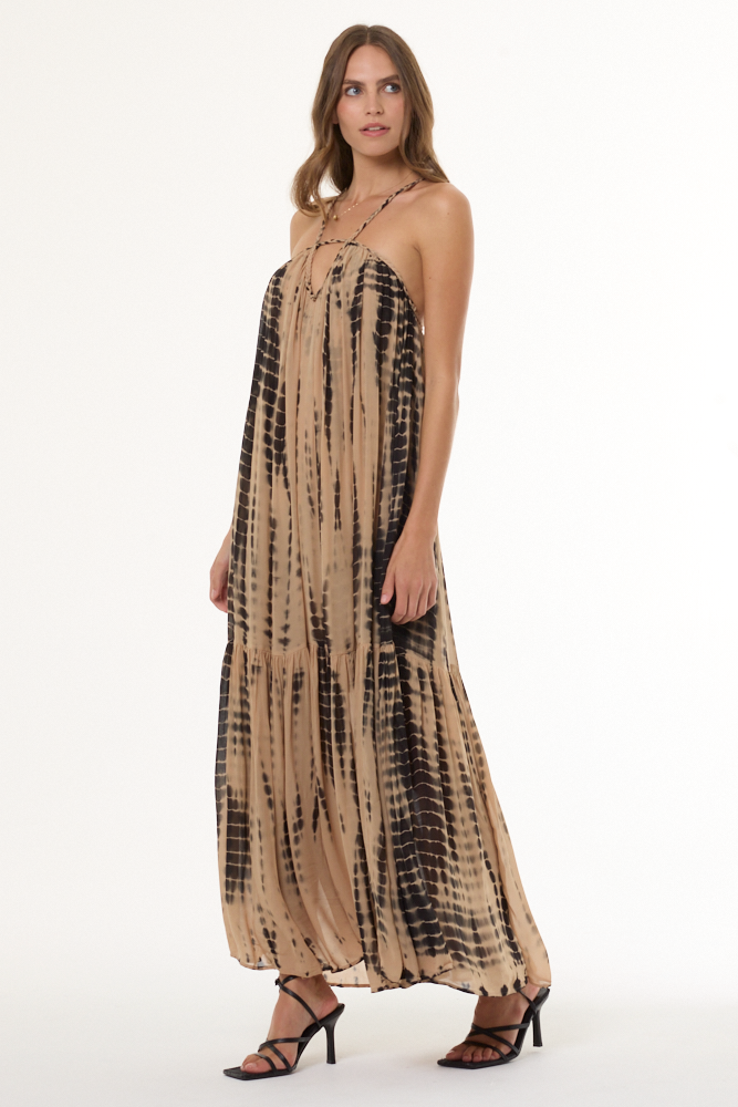 Woman wearing a tan and black tie-dye dress on a white background