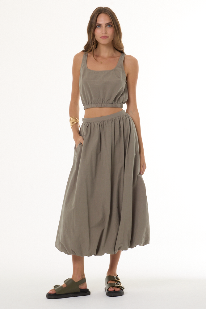 Woman wearing a beige sleeveless top and skirt set on a white background