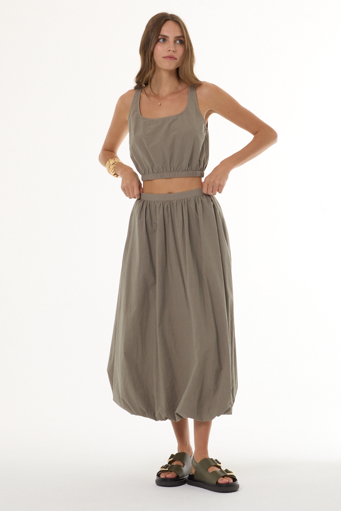 Woman wearing a matching beige top and skirt set on a white background