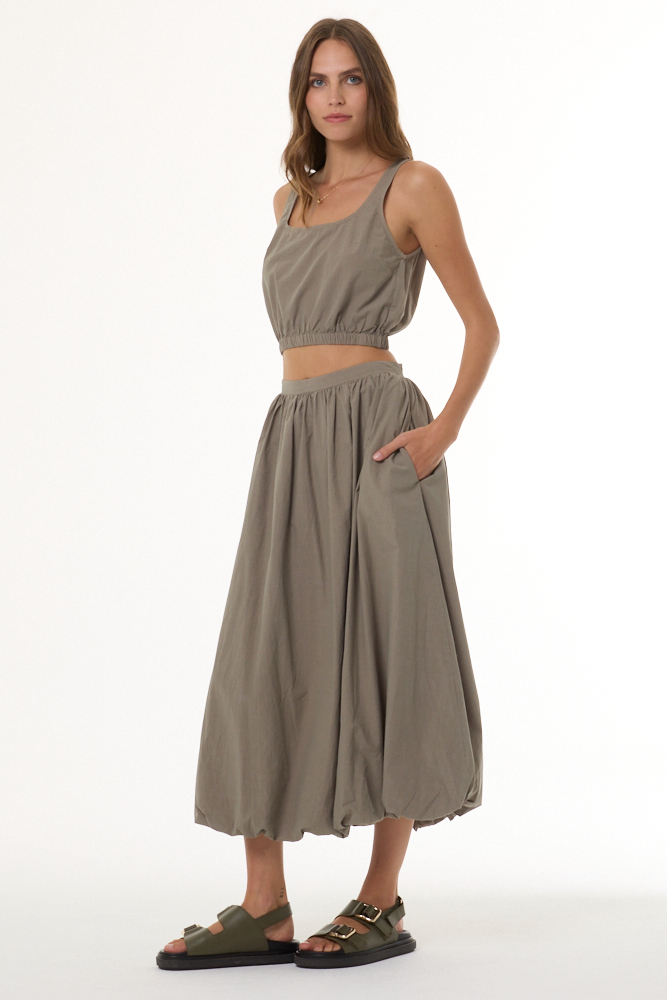 Woman wearing a matching beige top and skirt set on a white background