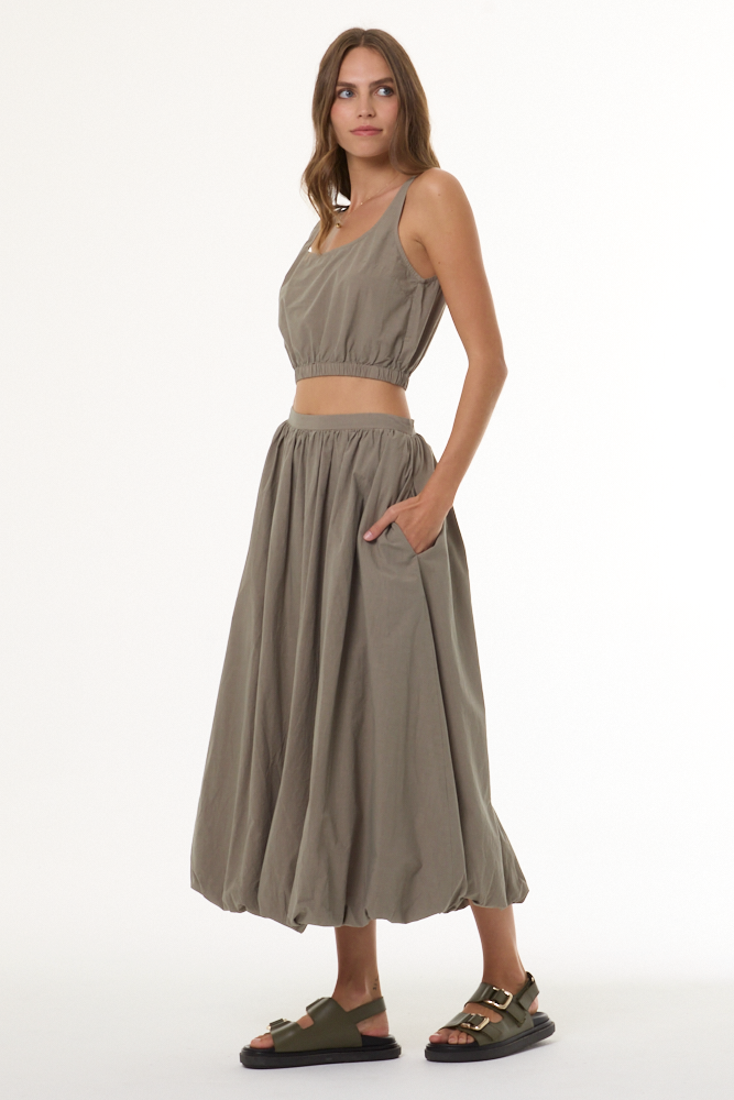 Woman wearing a matching beige top and skirt set on a white background