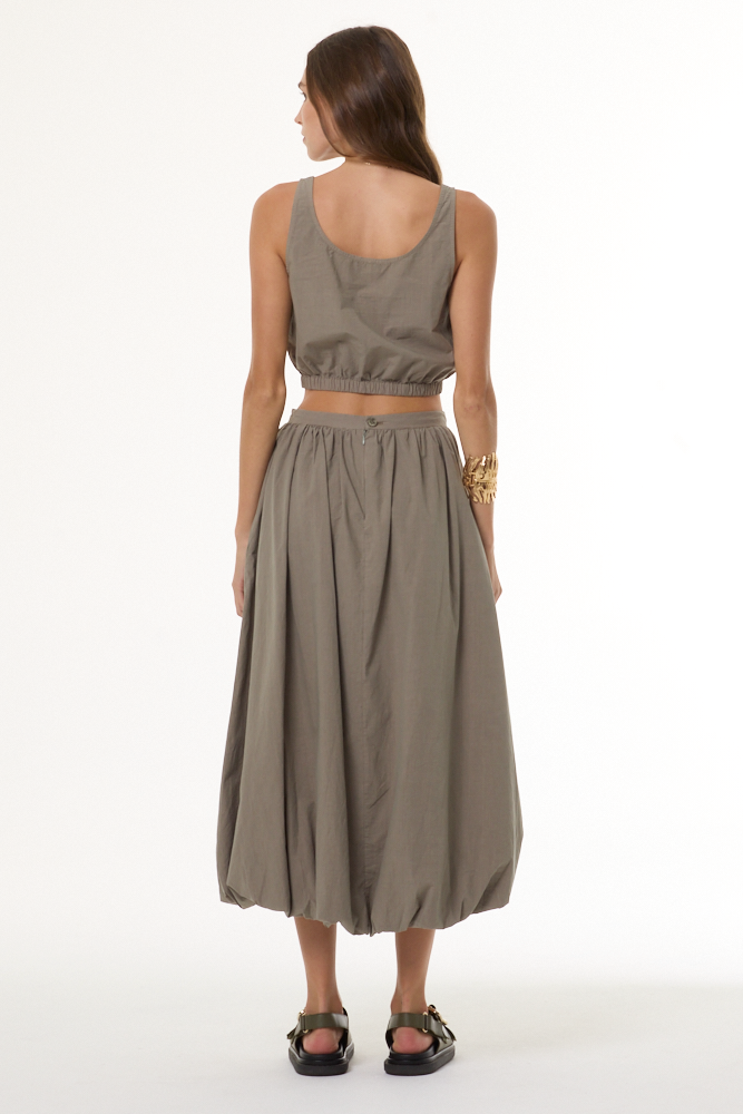 Woman wearing a matching beige top and skirt set on a white background