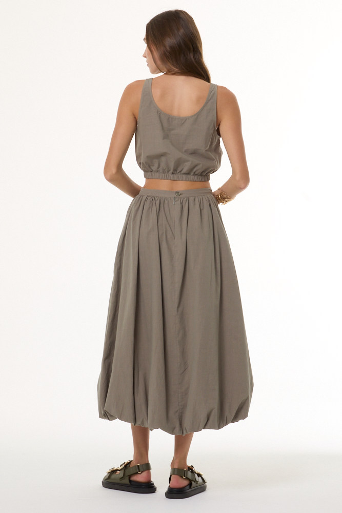 Woman wearing a matching beige top and skirt set on a white background