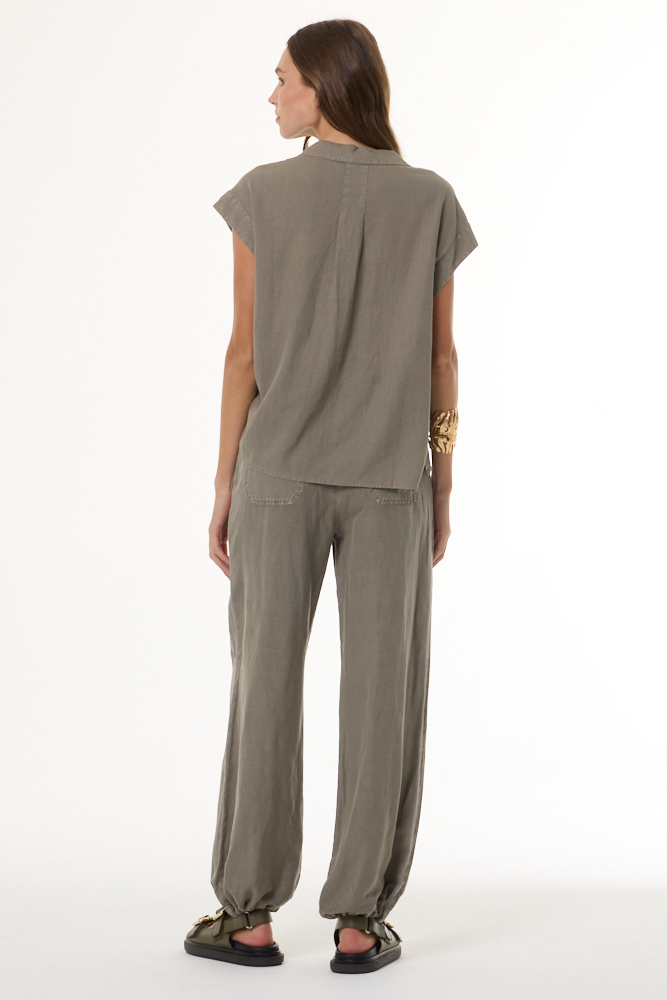 A woman shown from the back wearing a loose, short-sleeve top and matching wide-leg pants in a muted taupe-gray color, paired with black sandals, against a plain white studio background.