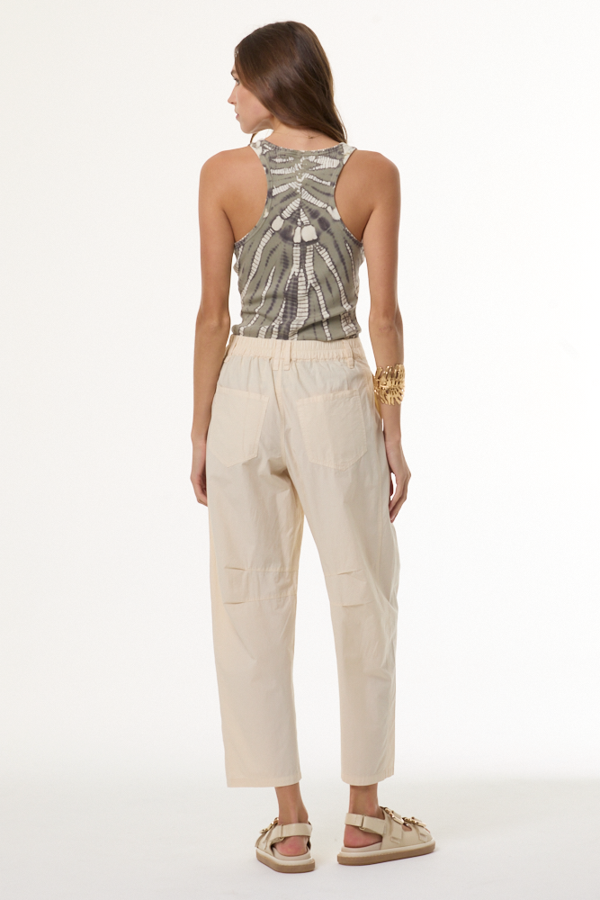 Woman wearing a patterned top and beige pants on a white background